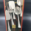 A boxed holiday serving ware set with silver-toned utensils visible through a red and gold package, photographed against a dark studio background. New Lenox Holiday 5-Piece Stainless Steel Serveware Hostess Set 
