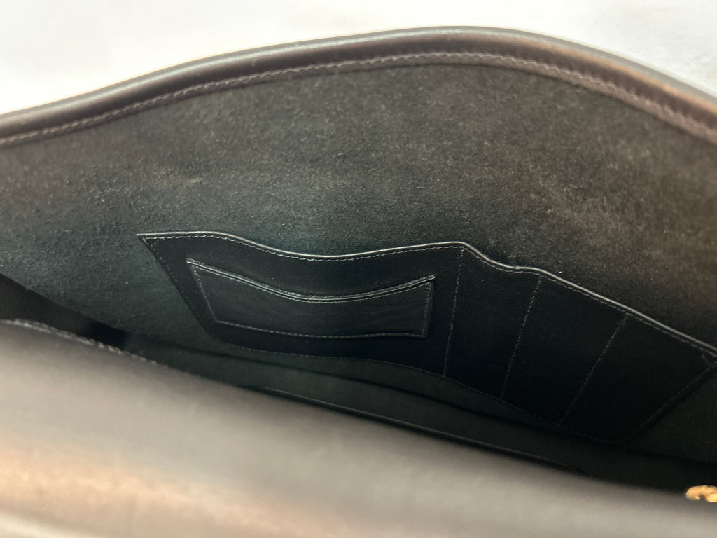 Close-up of the interior lining of a black leather Coach bag, showing a stitched pocket and interior structure.