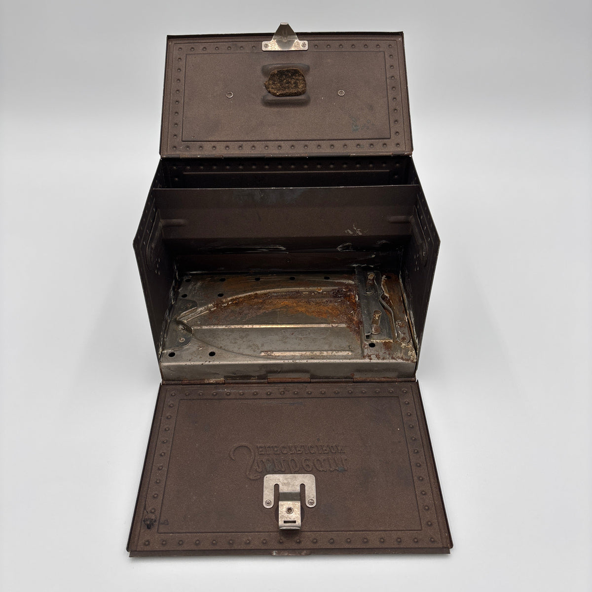 An antique dark brown metal storage chest or case, shown open to reveal its interior. The exterior has embossed rivets, a metal latch, and embossed branding on the lower front flap that reads 'BOSTONIAN'.