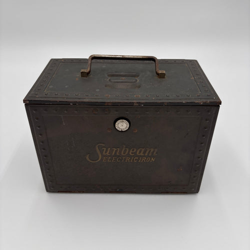 An antique dark brown metal Sunbeam Electric Iron case with a top handle, embossed rivets, and gold-toned branding on a light gray background.
