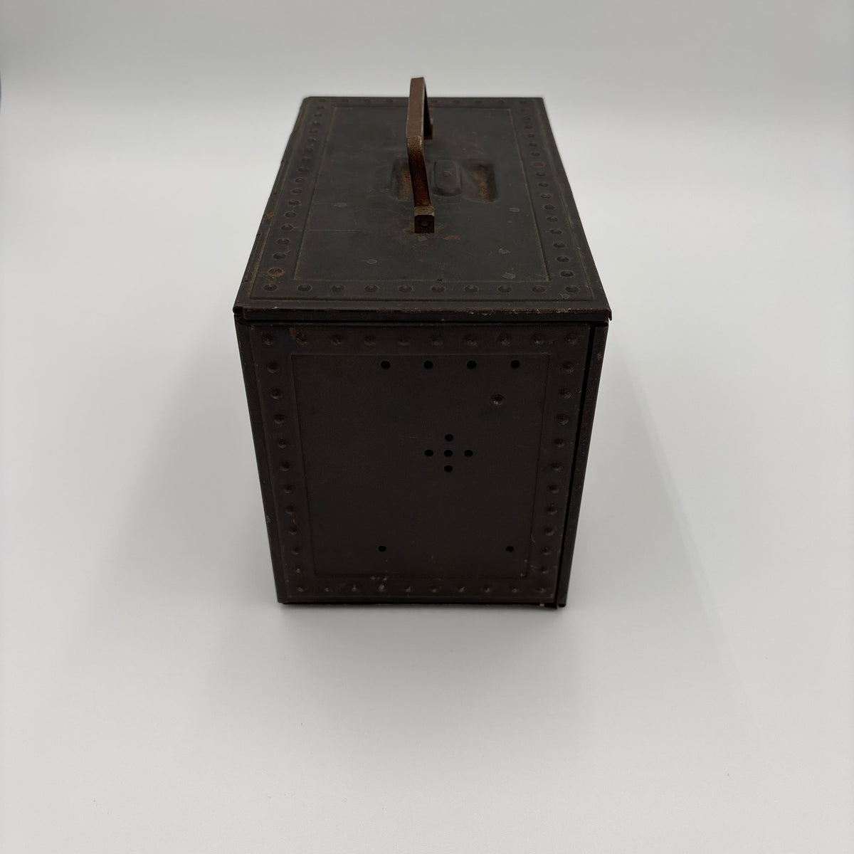 A dark brown rectangular metal box with a top handle, photographed on a seamless light gray studio background.