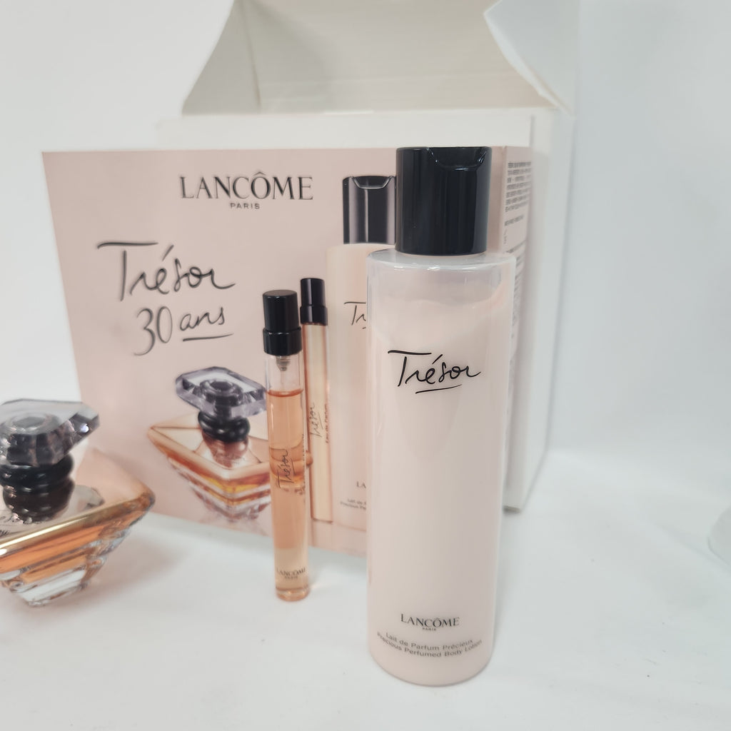 Lancôme Théor 30 ans body wash set, featuring a large pale pink bottle with a black cap, two small travel sample vials, and the product box in the background.