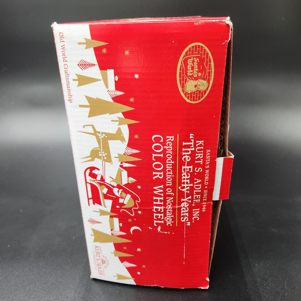 A red and white cardboard product box with gold holiday illustrations and text reading 'KIRT'S ADVENT INC. "The Early Years" Reproduction of Nostalgic Color Wheel'. Kurt Adler The Early Years Reproduction of the Nostalgic Color Wheel Light