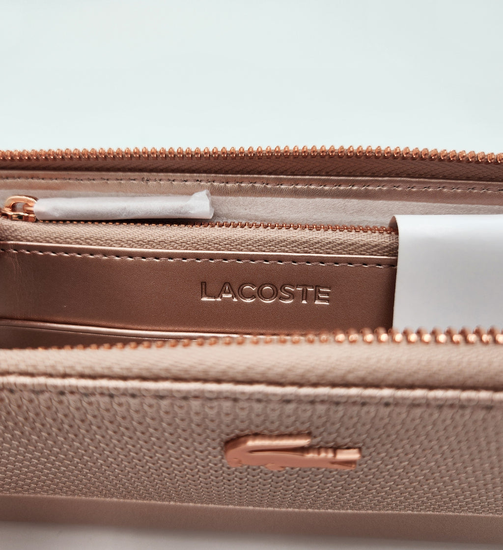 NWT Lacoste Chantaco Rose Gold Metallic Pique Leather Large Zip Around Wallet Clutch interior detail showcasing logo and zip pockets.