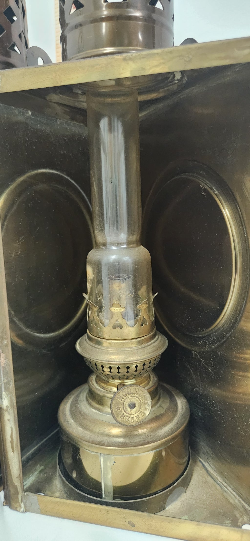 A vintage brass oil lamp with a clear glass chimney, set inside a matching brass metal case.