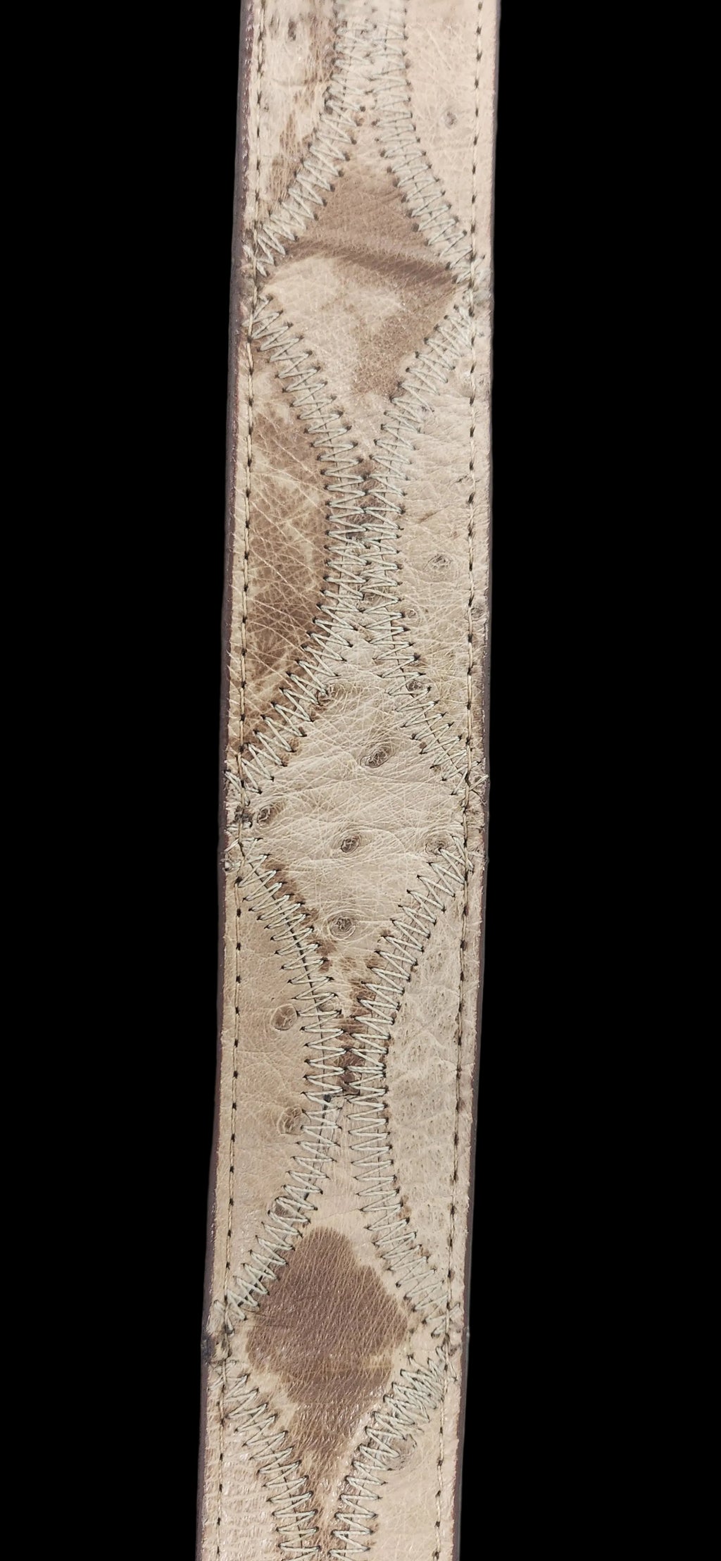 A close-up of a beige ostrich leather strap featuring a textured diamond pattern with decorative stitching.Justin Genuine Ostrich Belt
