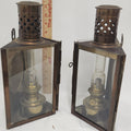Two vintage oil lanterns with dark bronze metal frames and clear glass panels, shown side by side with a wooden ruler for scale against a white background.