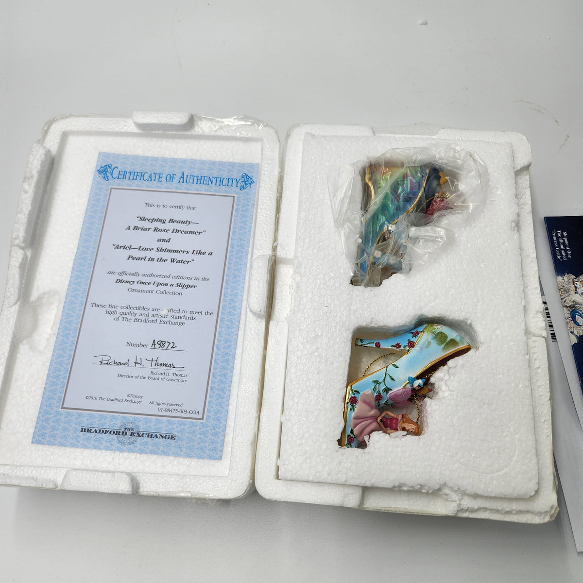 A collectible pair of illustrated glass tokens from 'Whaling Beauties: A Water Sport Streamer' by The Bradford Exchange, shown in their original white foam packaging with an authenticity certificate and a small booklet.