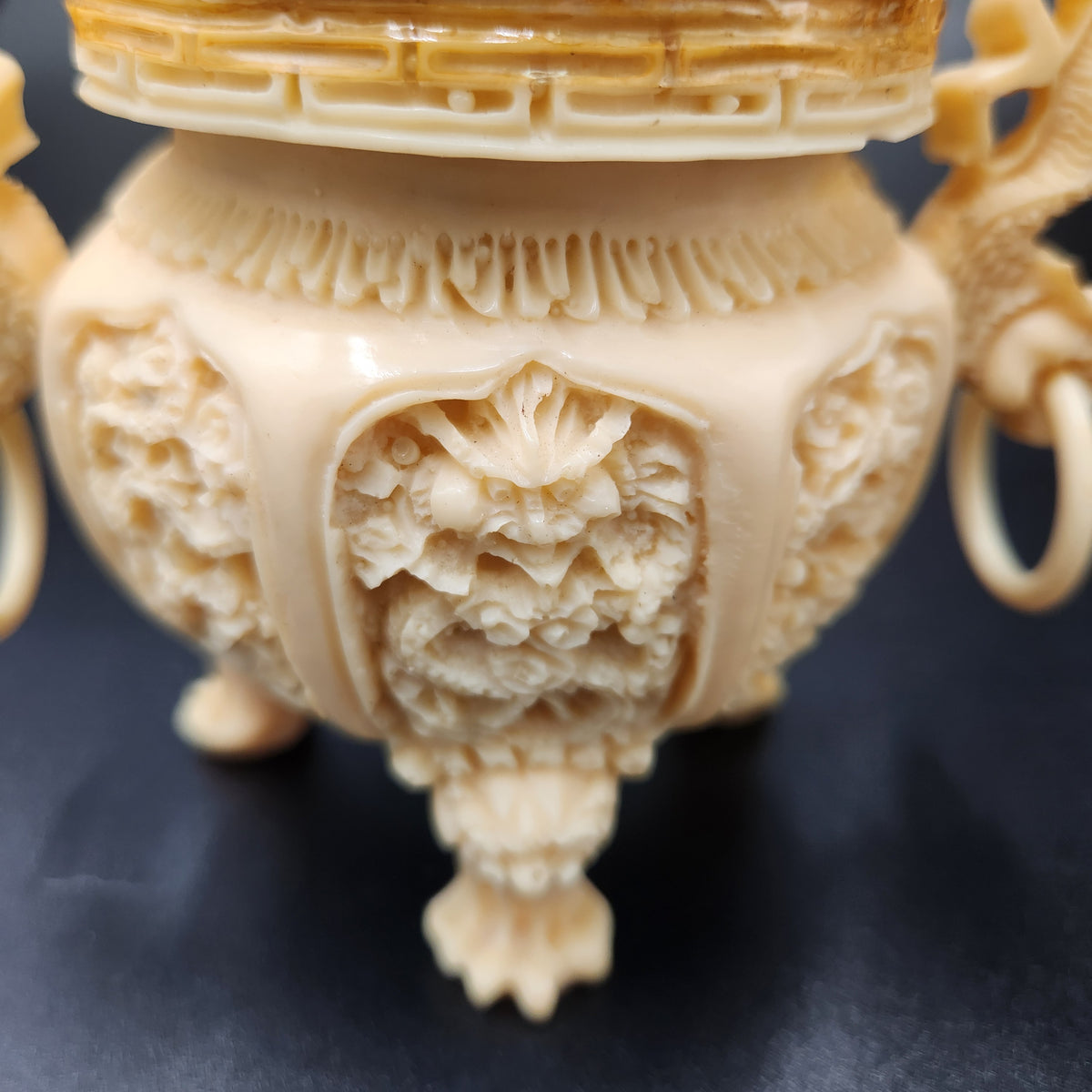 Close-up of an ornate carved ivory or bone decorative vessel with intricate floral and geometric relief details, shown against a dark background. Vintage Chinese Carved Resin Faux Ivory Incense Burners Tripod Censers 