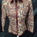 A long-sleeve button-front shirt jacket with an intricate paisley pattern in beige, rust red, and blue, displayed on a mannequin against a black fabric backdrop.