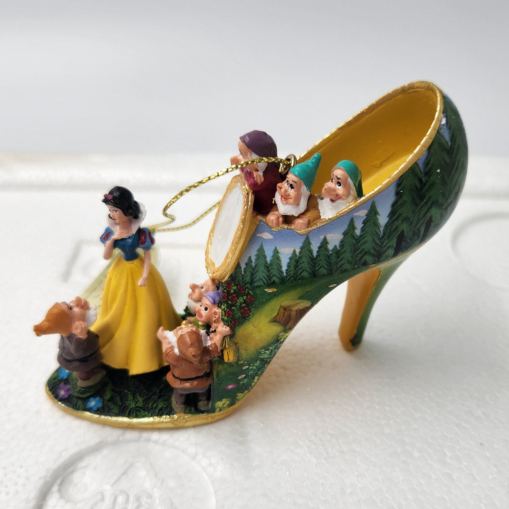A hand-painted Snow White and the Seven Dwarfs themed high-heeled shoe ornament, resting on a white styrofoam packaging insert.