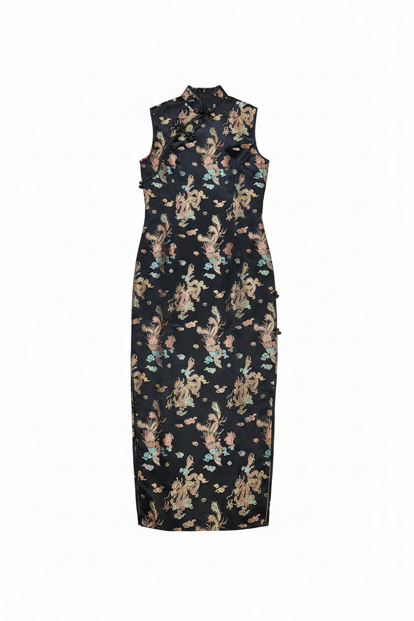 A sleeveless black cheongsam-style dress with a multicolor floral and bird pattern, laid flat on a white sheet in a room.