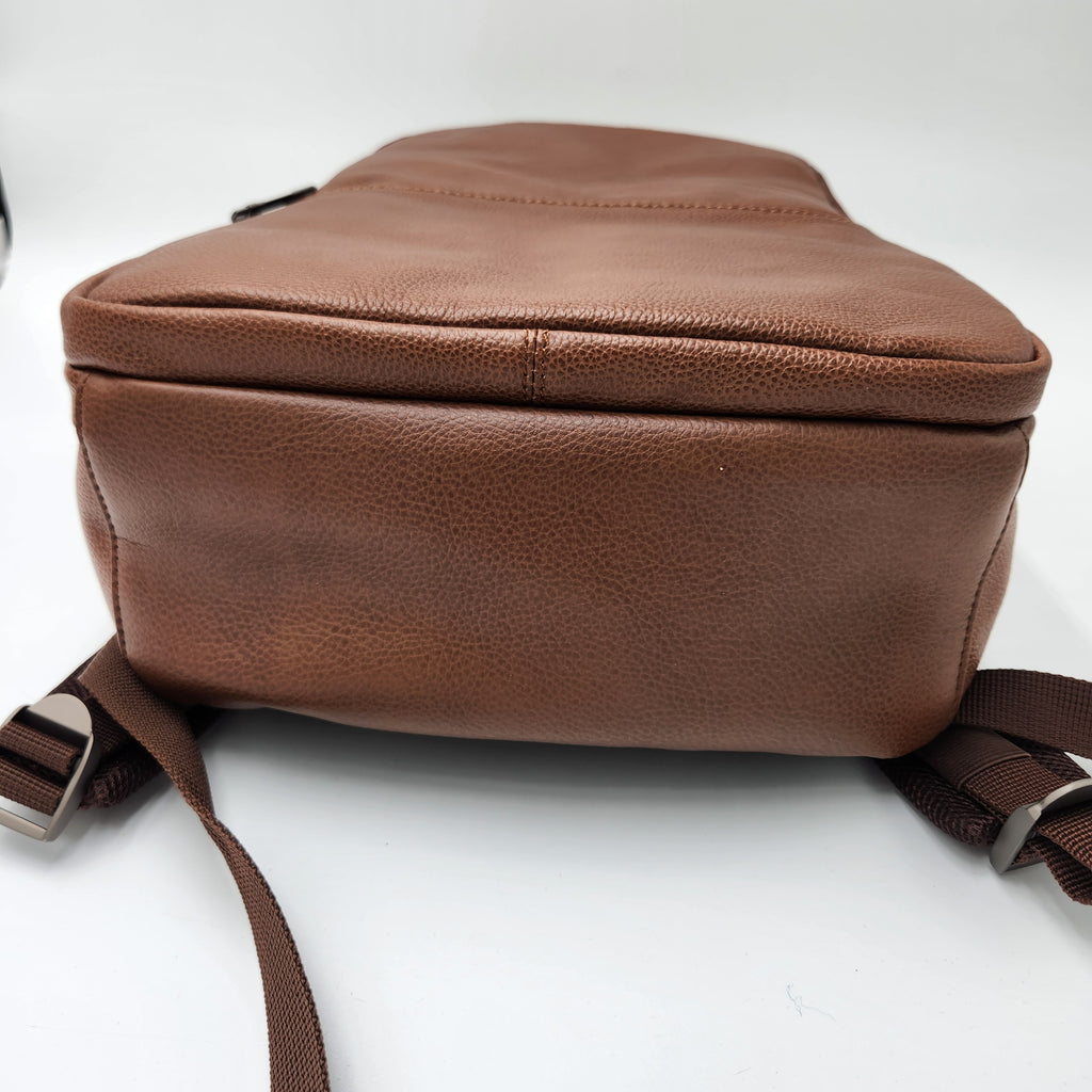 A brown pebbled leather laptop backpack with adjustable shoulder straps, shown from a side angle on a white background.