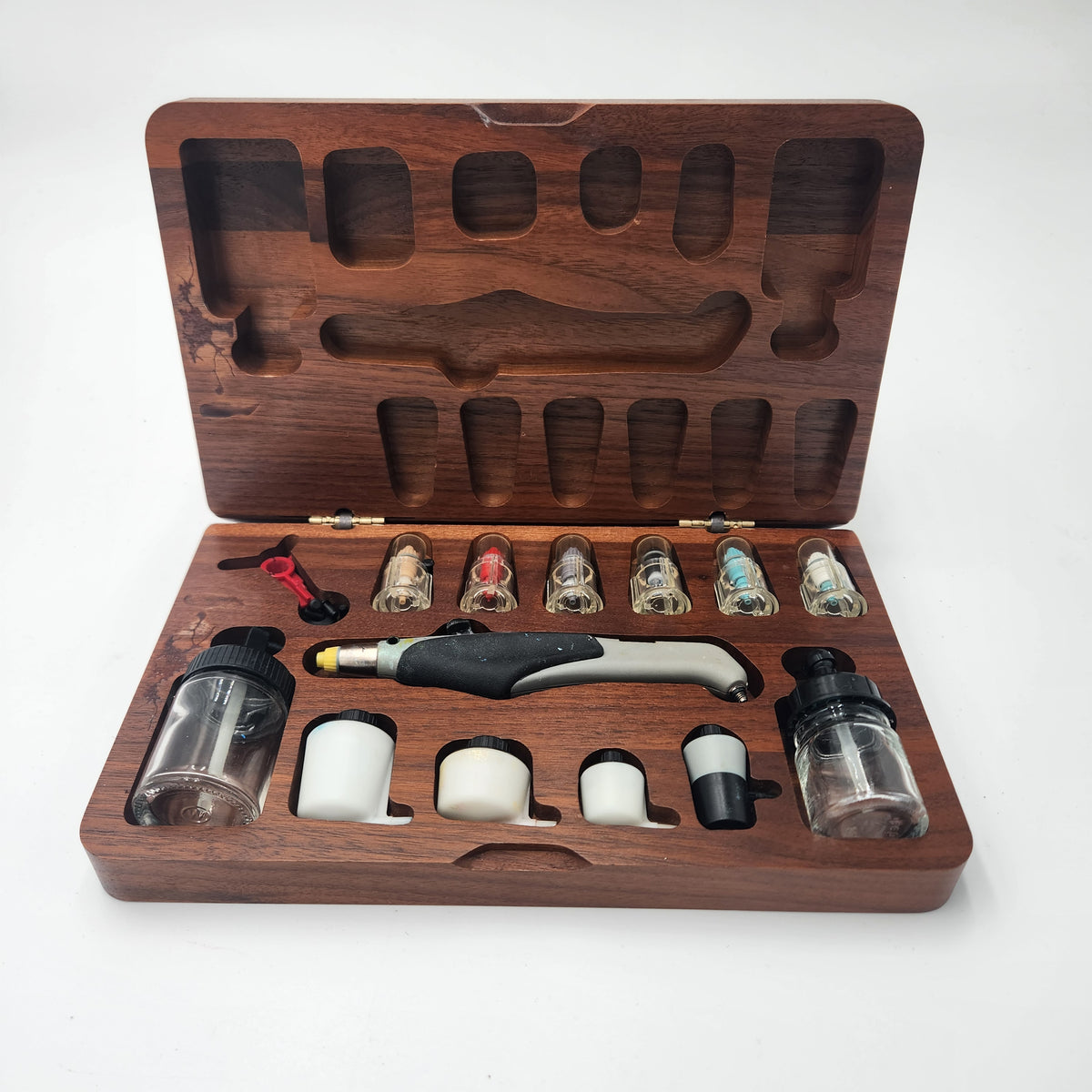 A wooden travel  kit set displayed in an open carved wooden case on a white background. 