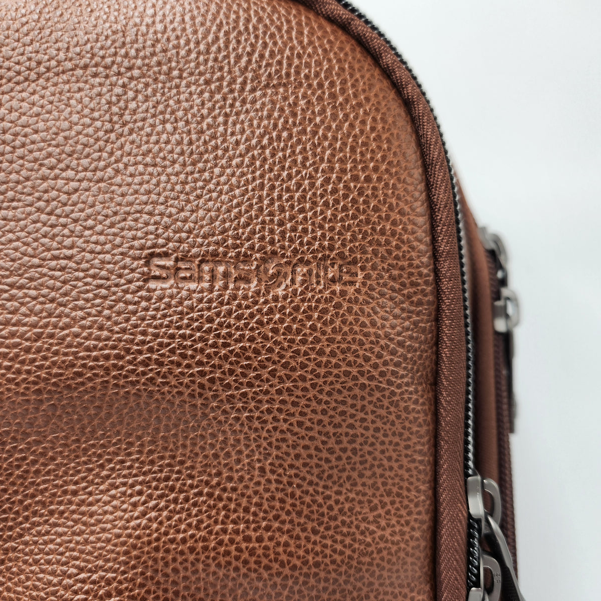 Close-up of a brown Samsonite pebbled leather bag with an embossed Samsonite logo and a silver zipper.