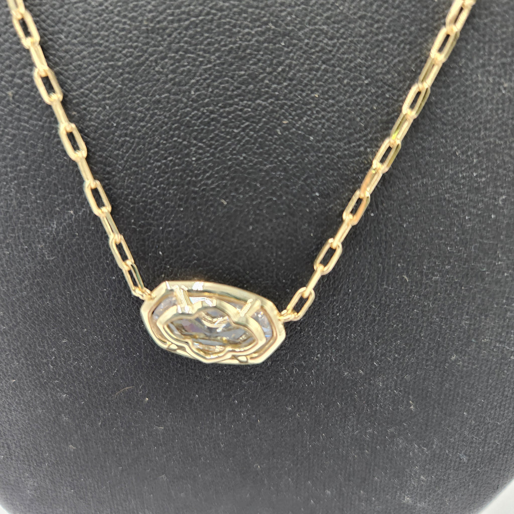 A gold chain necklace with an octagonal pendant featuring a textured, patterned inlay, displayed on a textured black background.