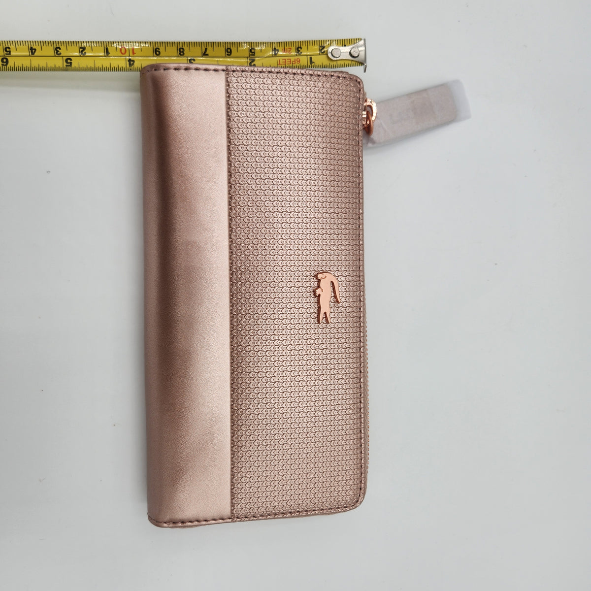 NWT Lacoste Chantaco Rose Gold Metallic Pique Leather Large Zip Around Wallet Clutch shown with measuring tape for size reference.