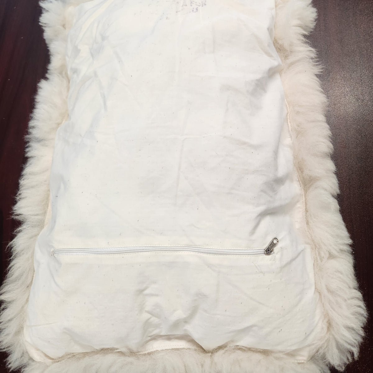 Vintage alpaca fur penguin pillow from Peru, front view of the black penguin motif on ivory plush fur showing zipper