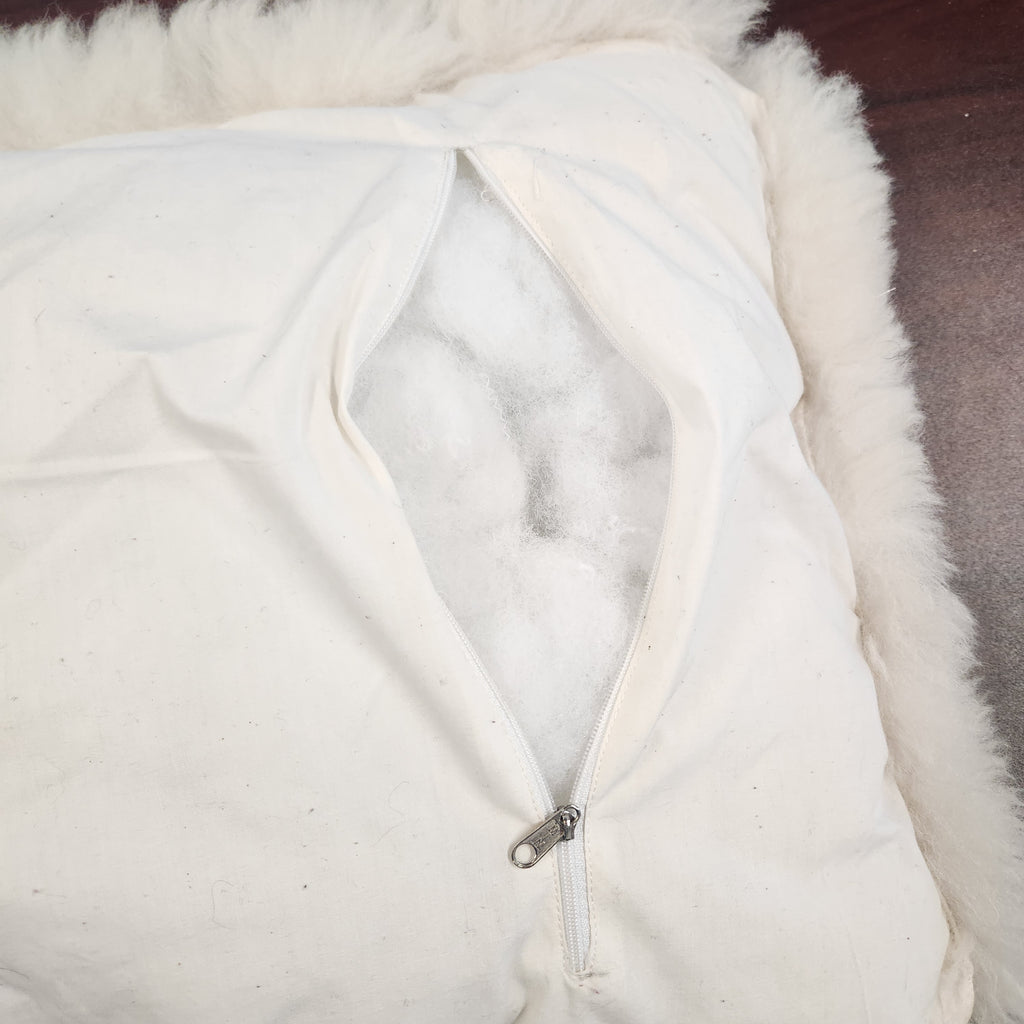 Vintage alpaca fur penguin pillow from Peru, front view of the black penguin motif on ivory plush fur stuffing inside